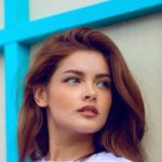 woman looking sideways leaning on white wall